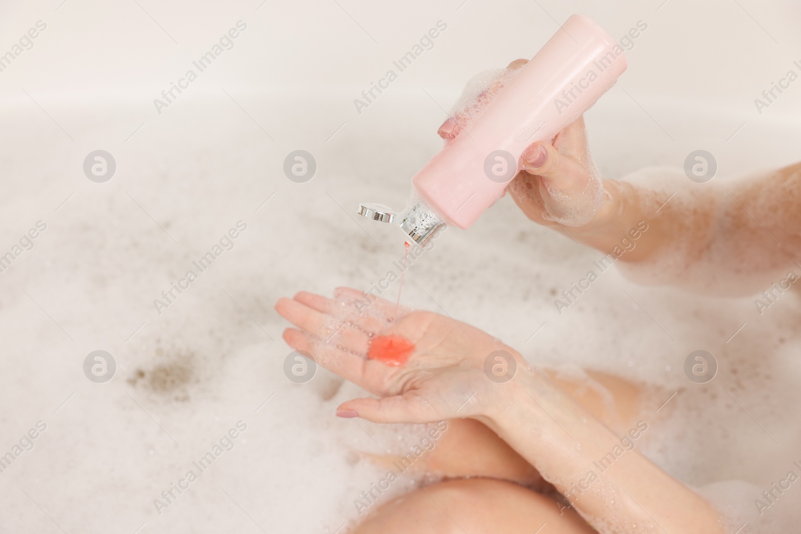 Photo of Woman pouring shower gel onto hand in bath indoors, closeup. Space for text