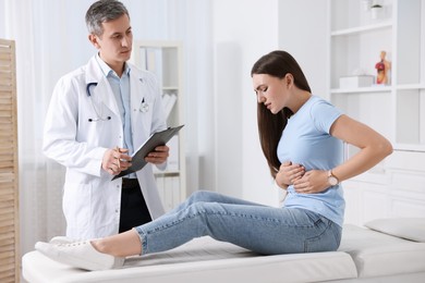 Gastroenterologist with clipboard consulting patient in clinic