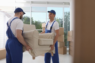 Photo of Moving service employees carrying armchair in room