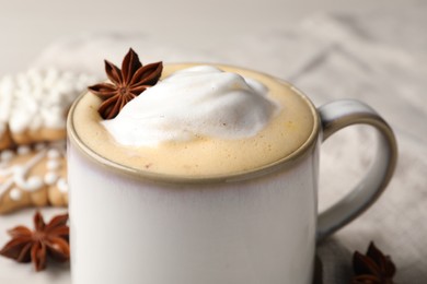 Cup of delicious eggnog with anise star on table, closeup