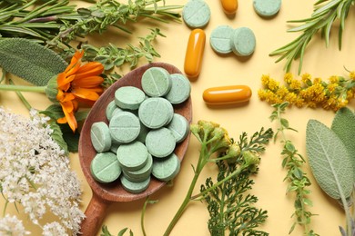 Different pills, herbs and flowers on pale orange background, flat lay. Dietary supplements