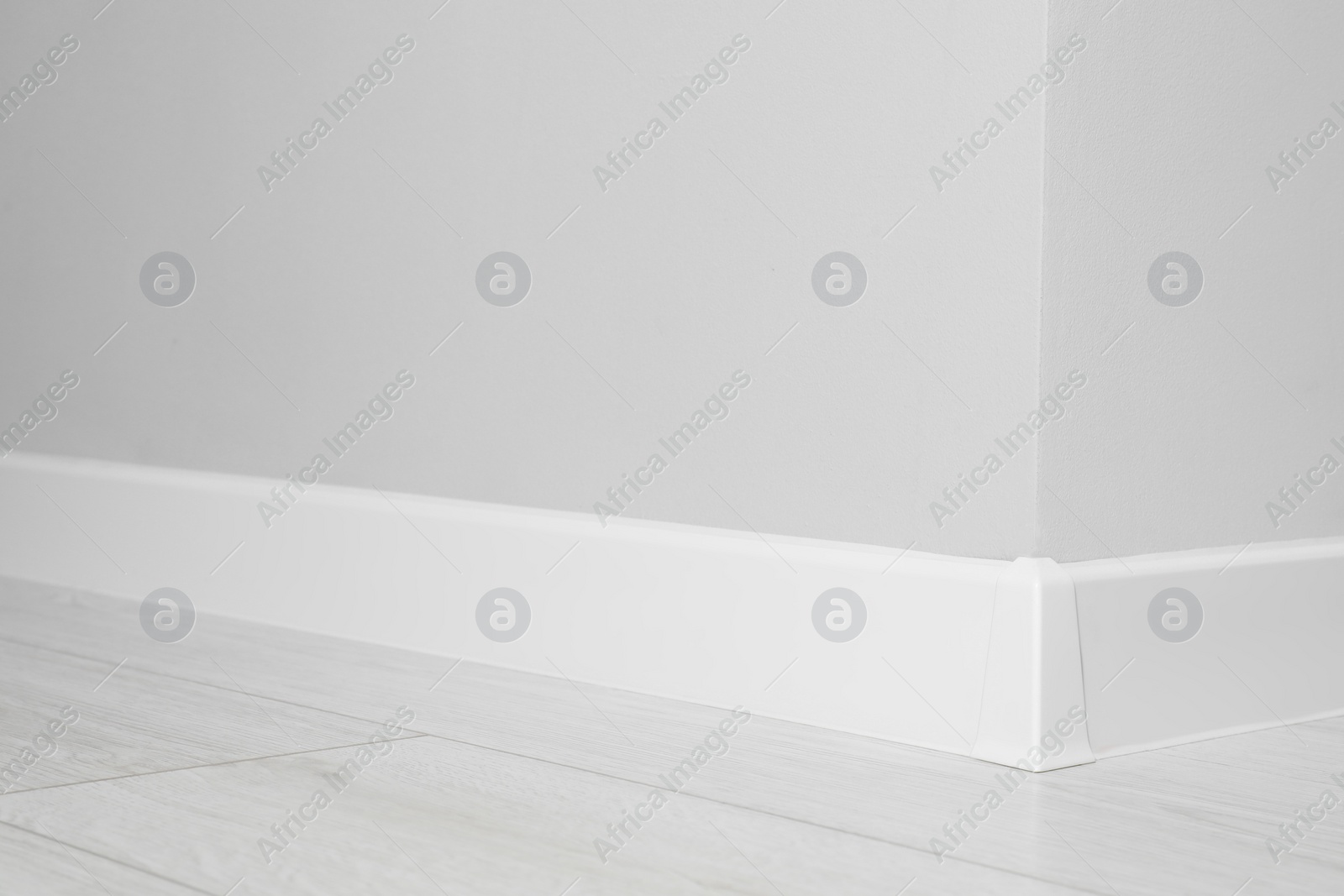 Photo of White plinth with connector on laminated floor near wall indoors, closeup