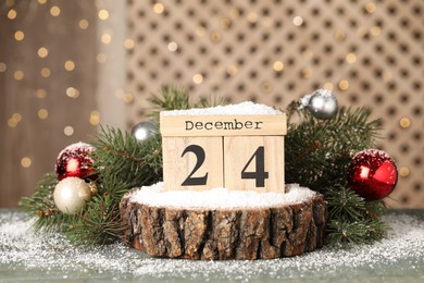 December 24 - Christmas Eve. Wooden block calendar and festive decor on grey table