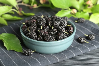 Photo of Delicious ripe black mulberries on dark wooden table, closeup