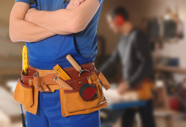 Carpenter with tool belt in workshop, closeup