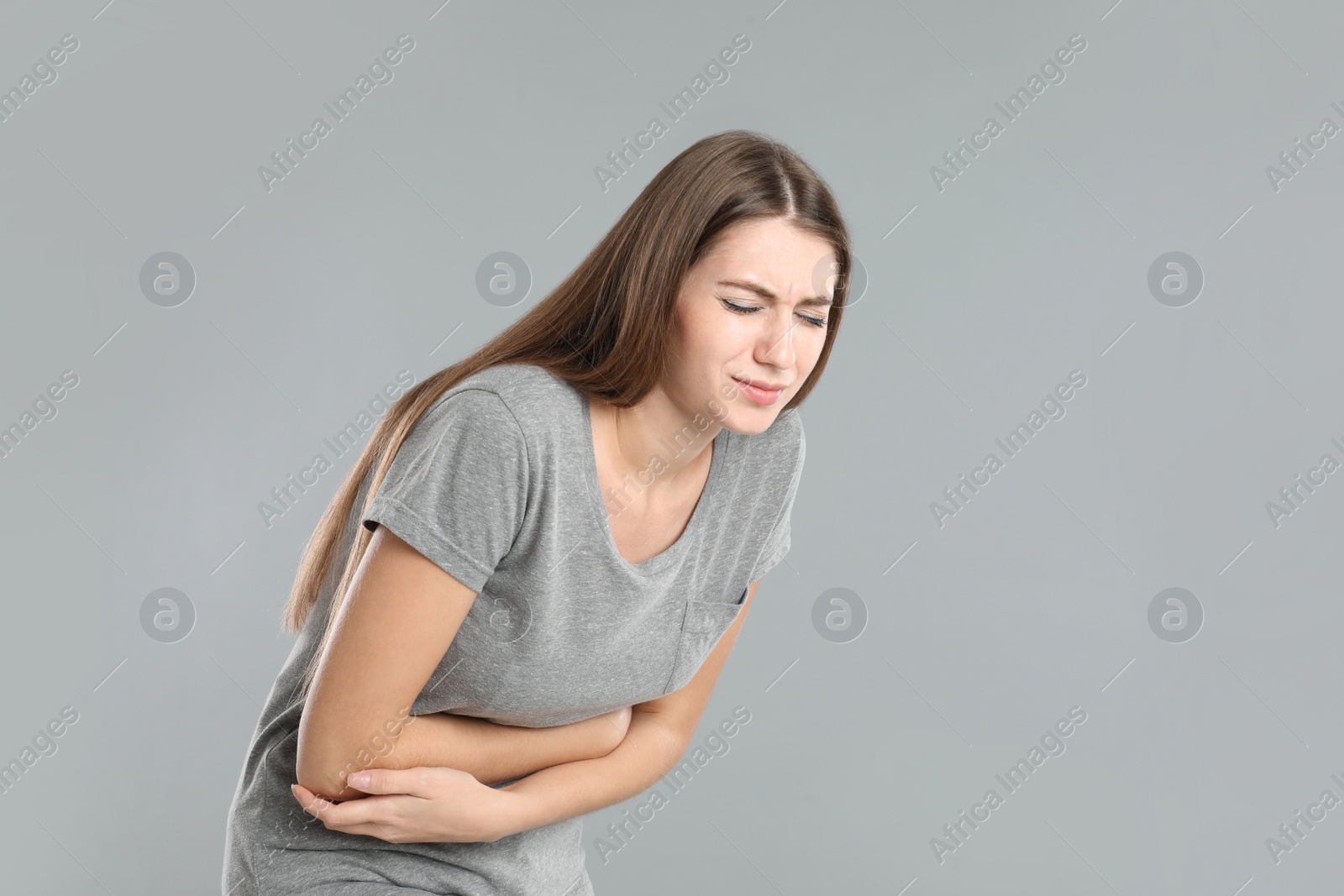 Photo of Woman suffering from stomach ache on grey background, space for text. Food poisoning
