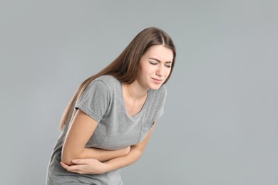 Photo of Woman suffering from stomach ache on grey background, space for text. Food poisoning