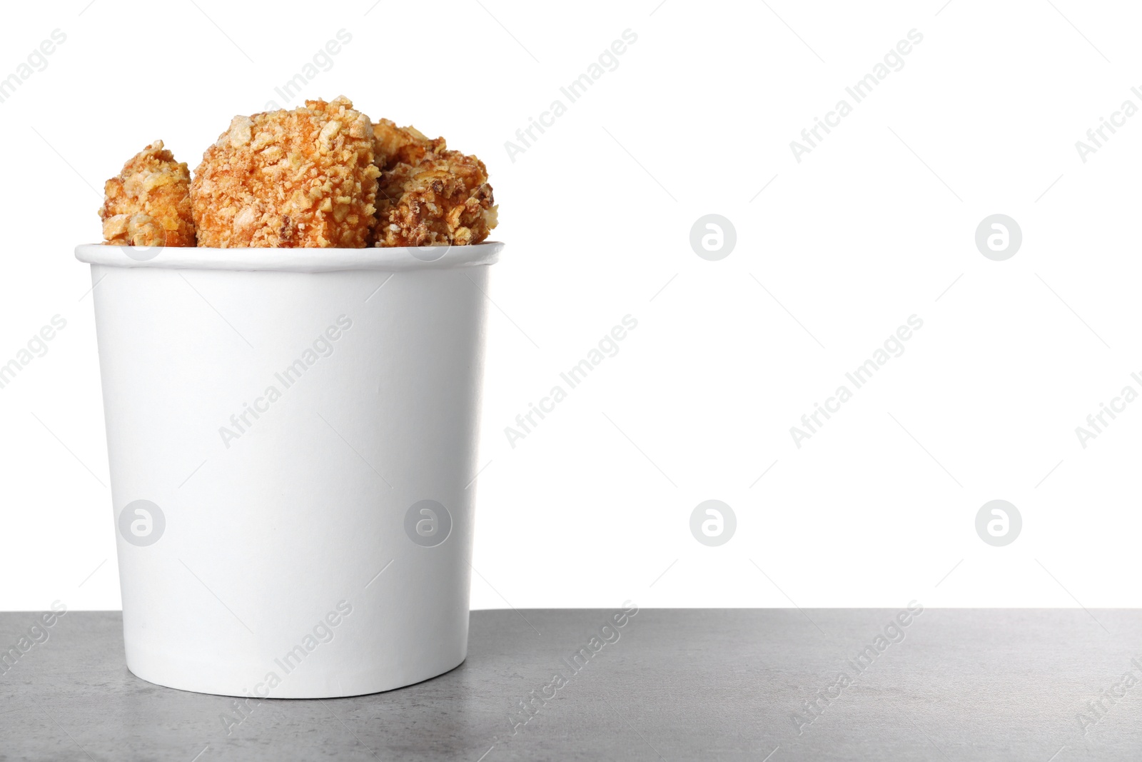 Photo of Bucket with yummy nuggets on dark table against white background, space for text