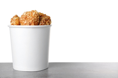 Photo of Bucket with yummy nuggets on dark table against white background, space for text