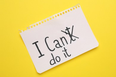 Photo of Motivation concept. Changing phrase from I Can't Do It into I Can Do It by crossing out letter T on yellow background, top view