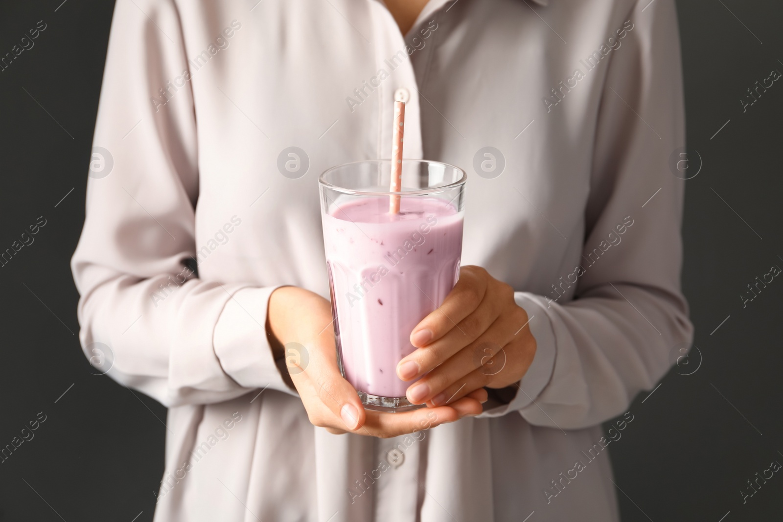 Photo of Woman holding fig smoothie on grey background, closeup
