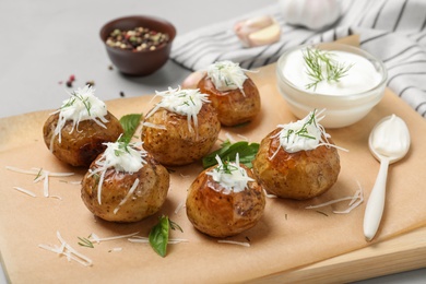 Photo of Delicious baked potato with sour cream on wooden board