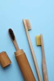 Bamboo toothbrushes on light blue background, flat lay
