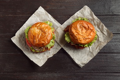 Photo of Delicious burgers with bacon on wooden table, top view