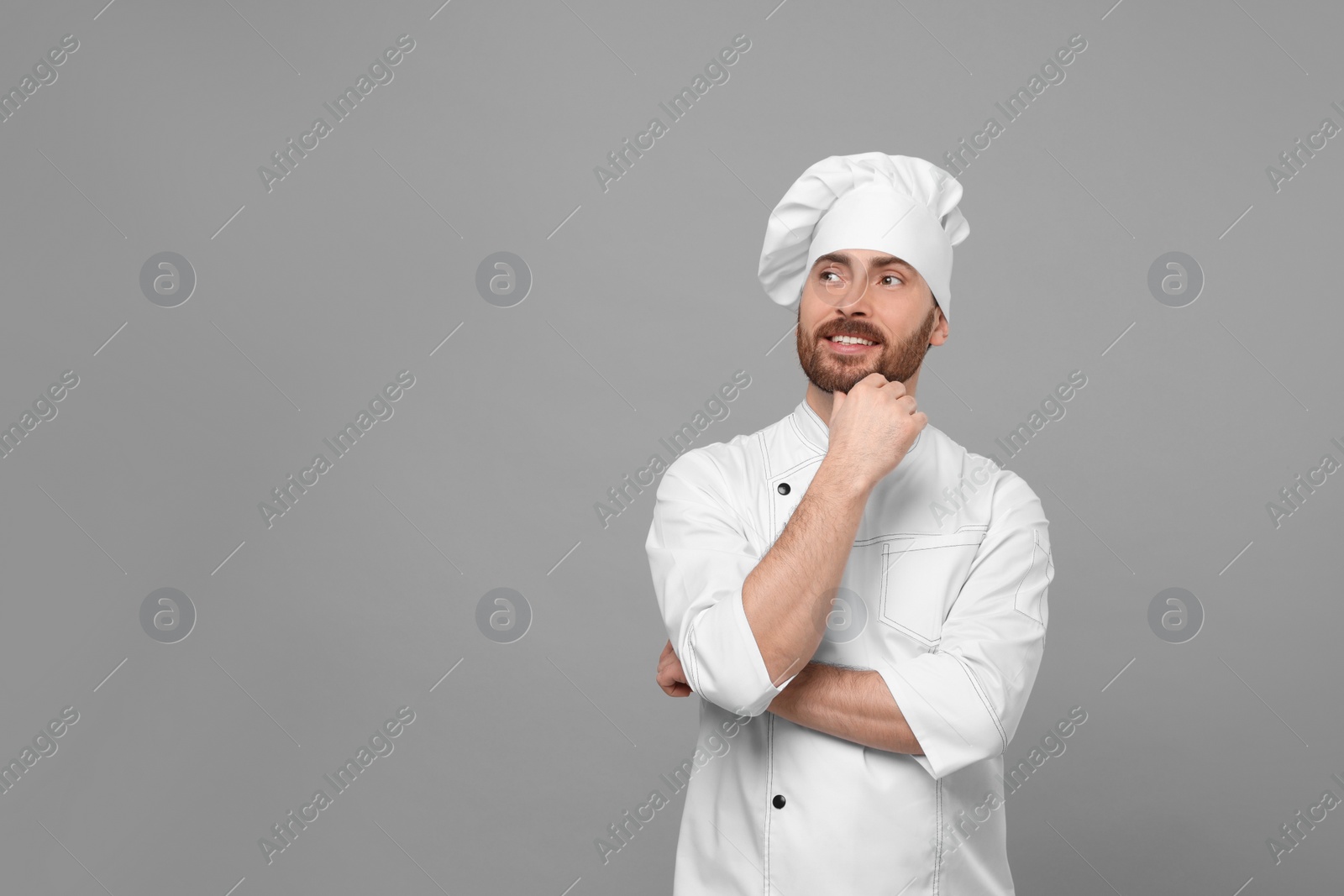 Photo of Smiling mature chef on grey background, space for text