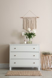 Photo of Room interior with white chest of drawers near beige wall