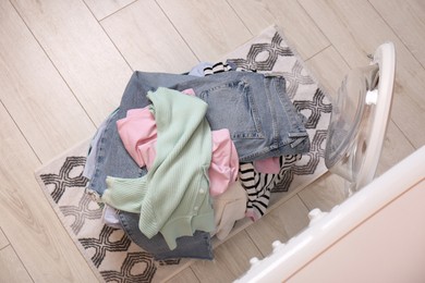 Photo of Laundry basket with clothes on floor near washing machine in bathroom, top view