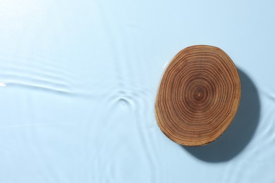 Photo of Presentation of product. Wooden podium in water on light blue background, top view. Space for text