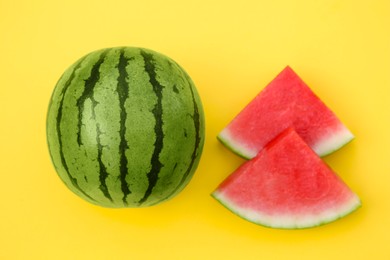 Delicious cut and whole ripe watermelons on yellow background, flat lay