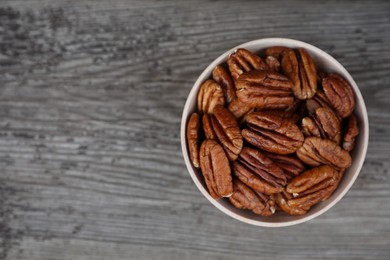 Photo of Tasty pecan nuts on grey wooden table, top view. Space for text