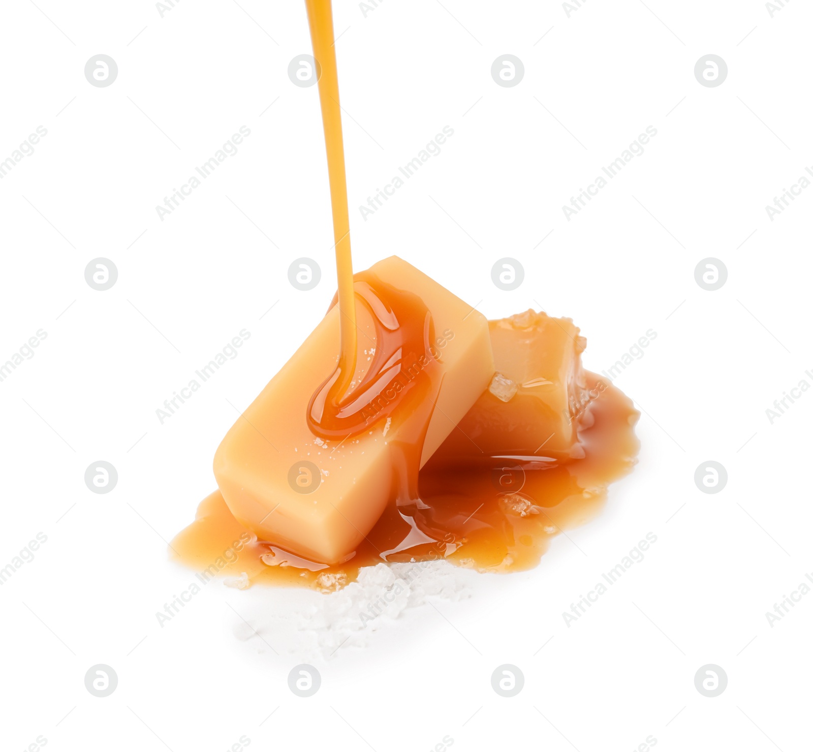 Photo of Pouring delicious salted caramel on candies isolated on white