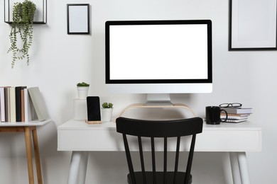 Photo of Cozy workspace with computer, smartphone and stationery on wooden desk at home