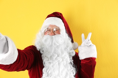 Photo of Authentic Santa Claus taking selfie on yellow background