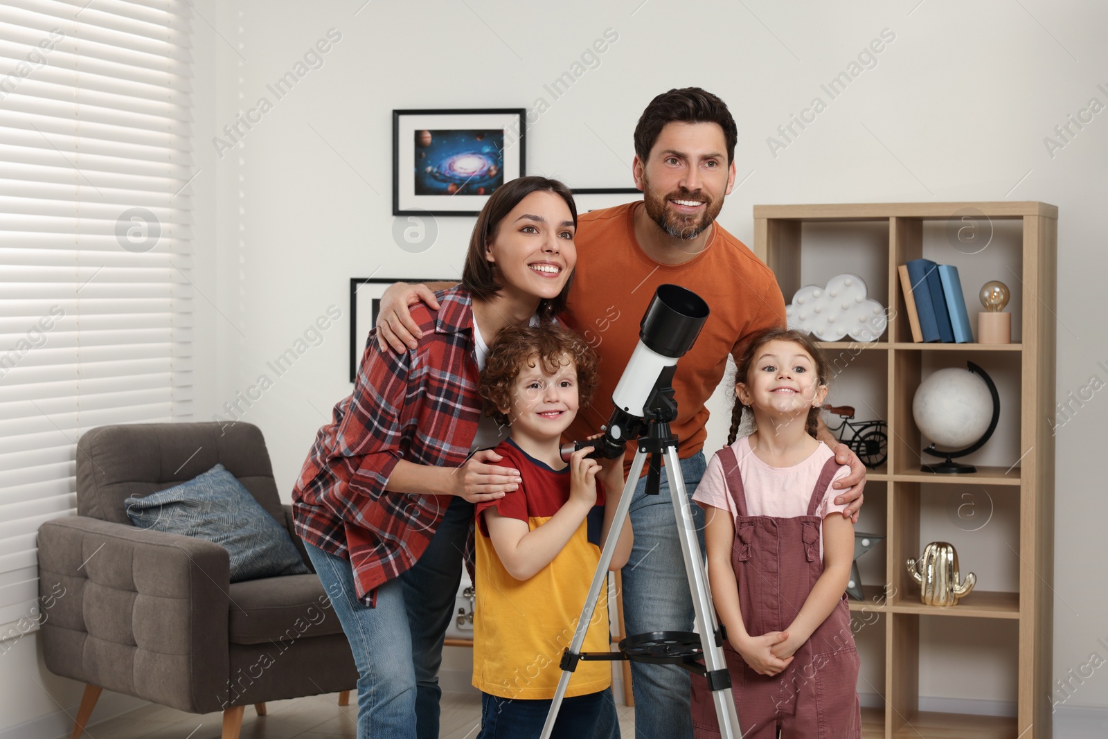 Photo of Happy family looking at stars through telescope in room