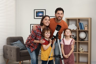 Happy family looking at stars through telescope in room