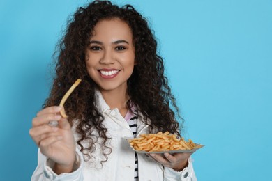 Photo of African American woman with French fries on light blue background, space for text