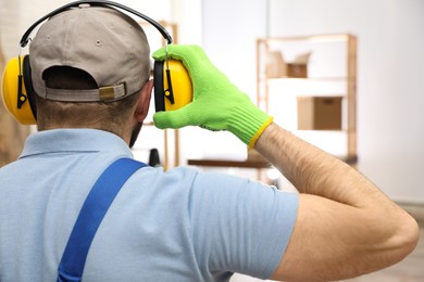 Photo of Worker wearing safety headphones indoors, back view. Hearing protection device