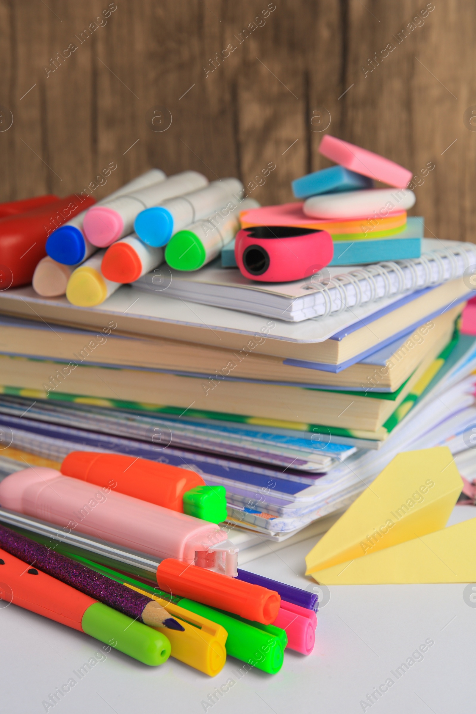 Photo of Many different books, paper plane and school stationery on white table, closeup. Back to school