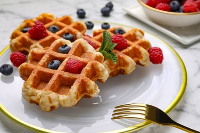 Delicious Belgian waffles with fresh berries and mint on table, closeup
