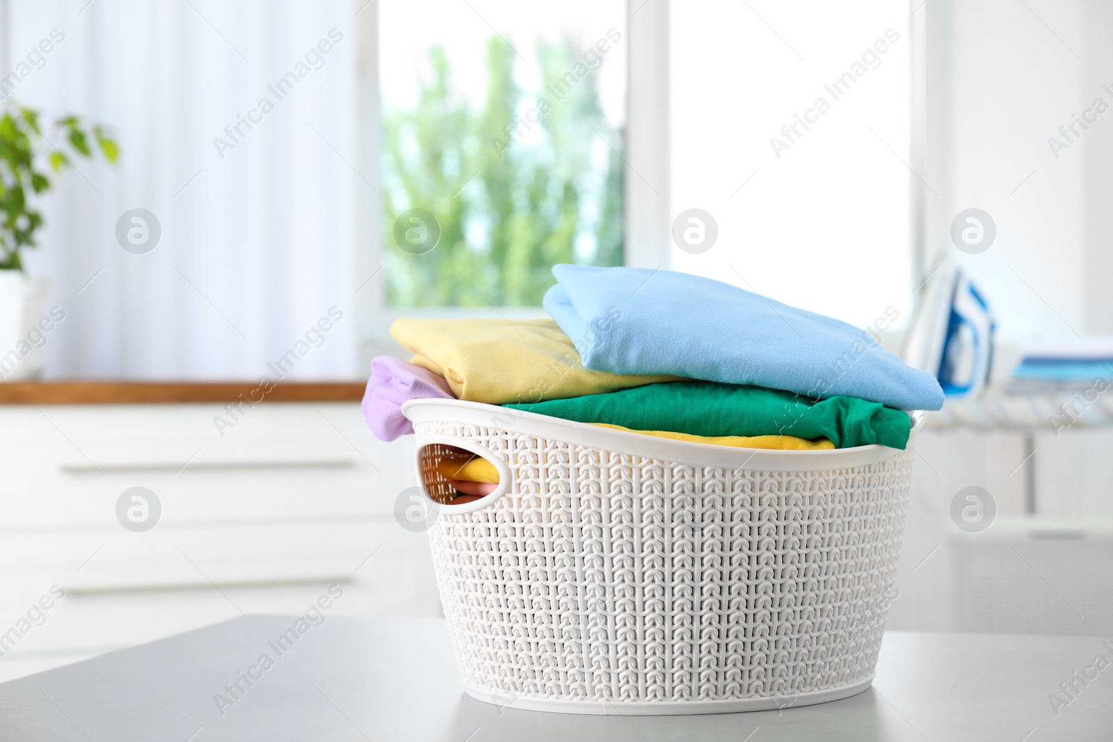 Photo of Basket with clean laundry on table at home, space for text