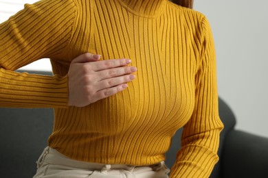 Photo of Mammology. Young woman doing breast self-examination at home, closeup