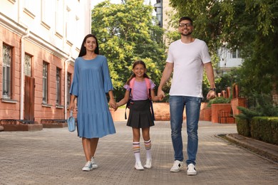 Parents taking their daughter to school in morning