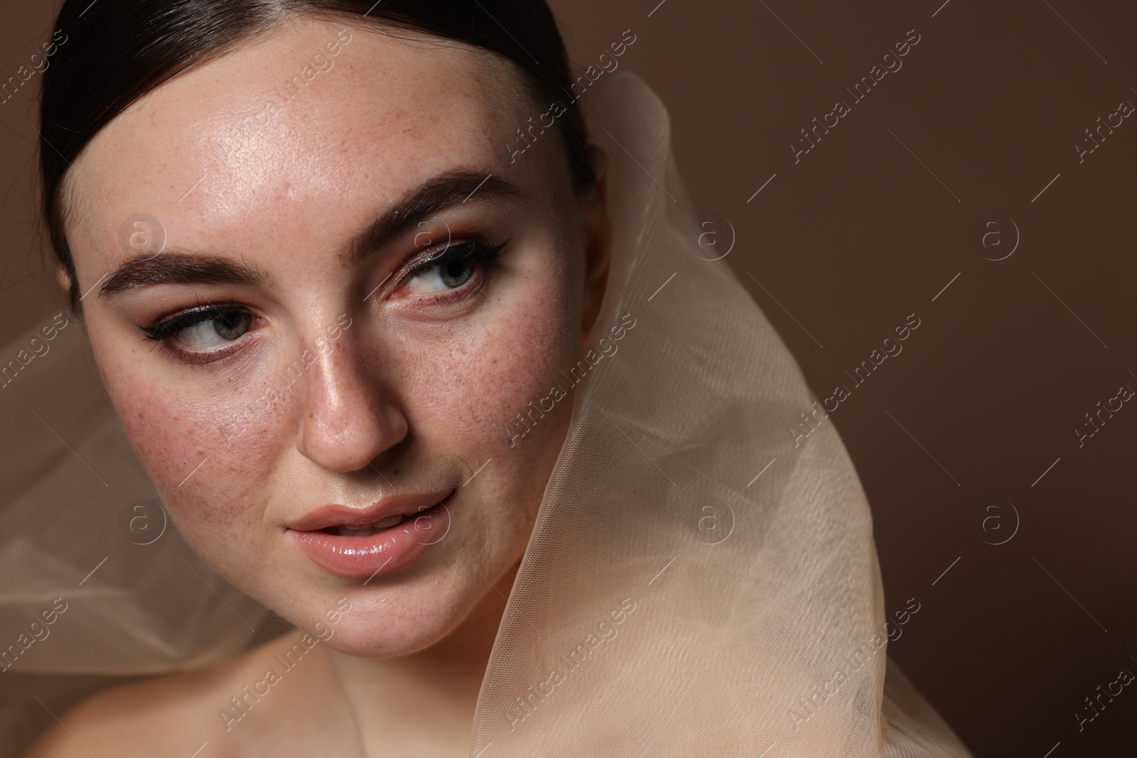 Photo of Fashionable portrait of beautiful woman with fake freckles on brown background, closeup
