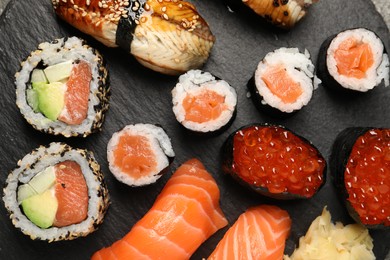 Photo of Set of delicious sushi rolls on slate board, top view