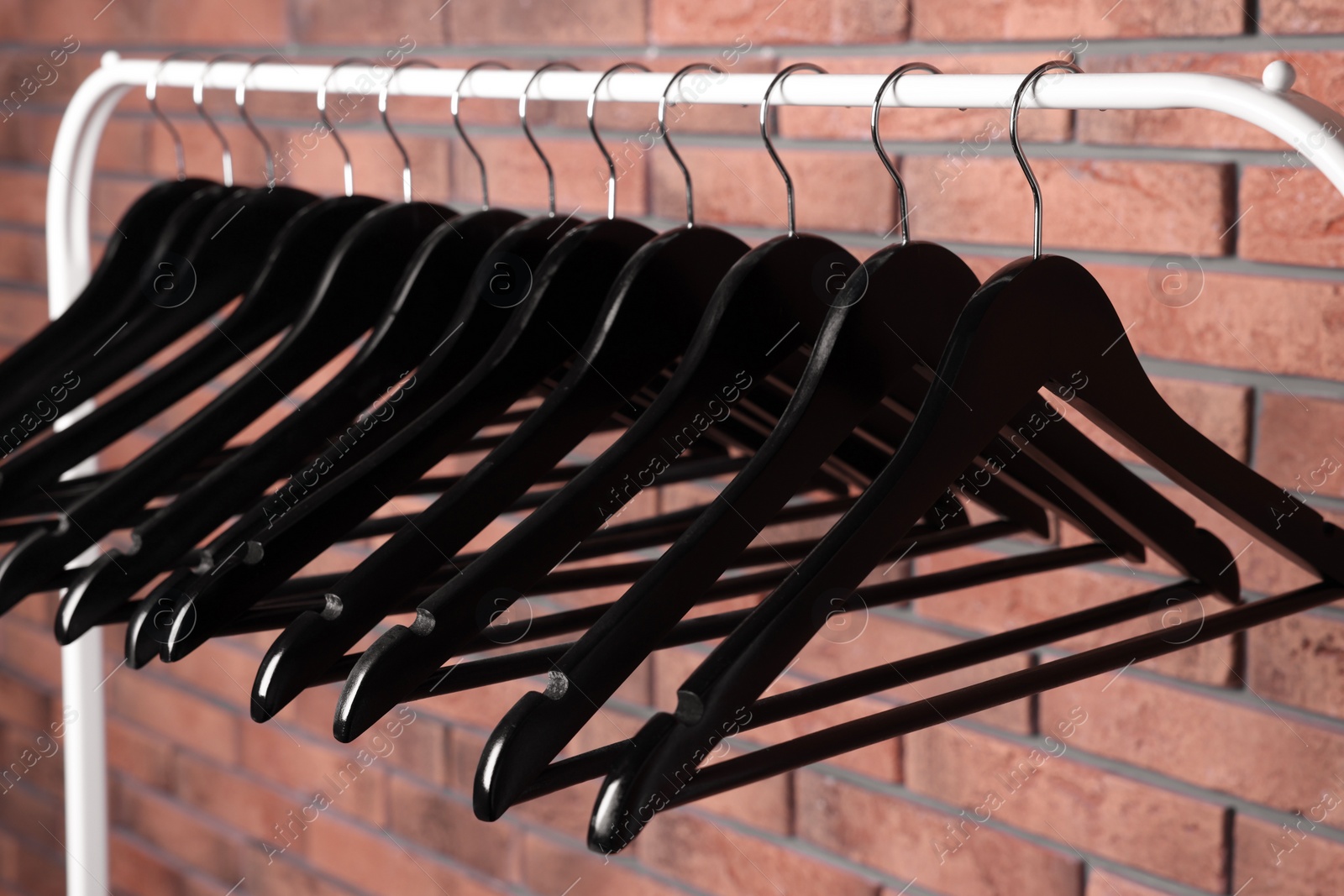 Photo of Black clothes hangers on rack near red brick wall