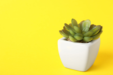 Beautiful artificial plant in flower pot on yellow background, space for text