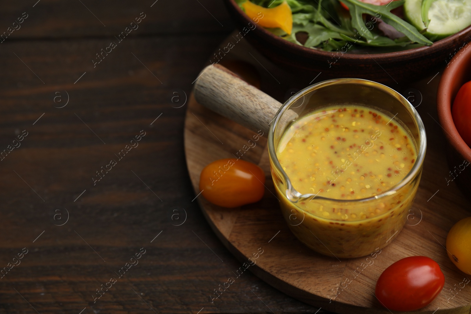 Photo of Tasty vinegar based sauce (Vinaigrette), salad and tomatoes on wooden table, closeup. Space for text