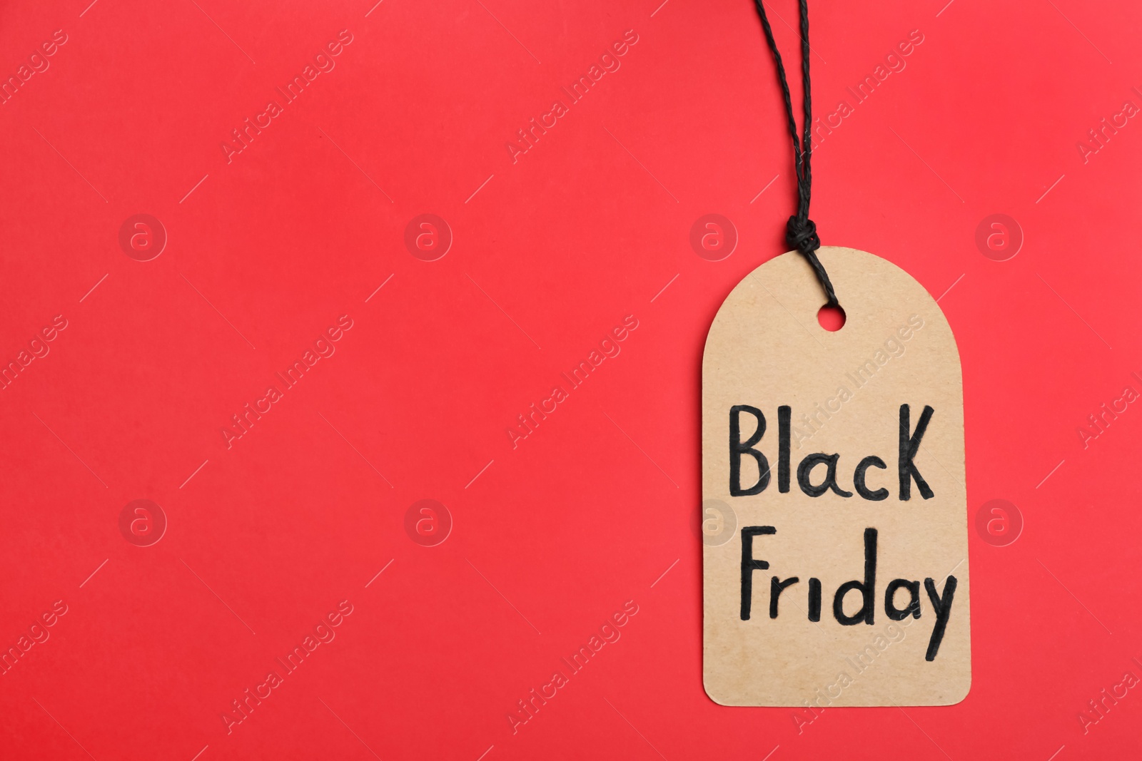 Photo of Tag with words BLACK FRIDAY on red background, top view. Space for text