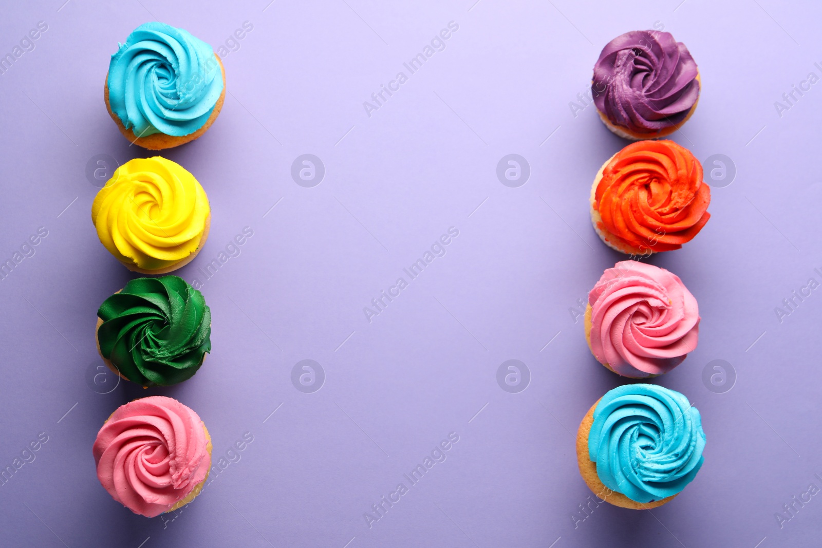 Photo of Delicious cupcakes with bright cream on violet background, flat lay. Space for text