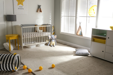 Photo of Cute baby room interior with crib and decor elements
