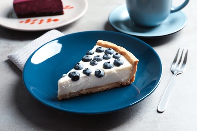 Plate with piece of tasty blueberry cake on gray table