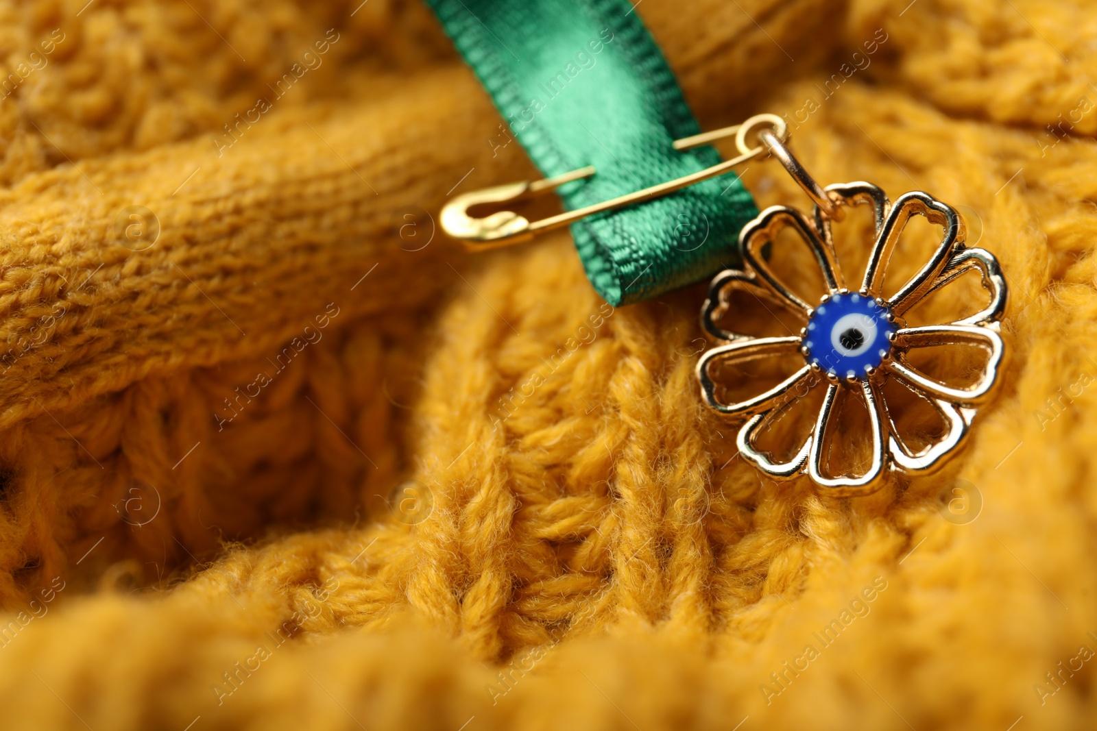 Photo of Evil eye safety pin on knitted clothing, closeup