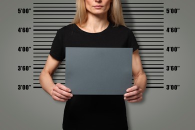 Image of Criminal mugshot. Arrested woman with blank card against height chart, closeup