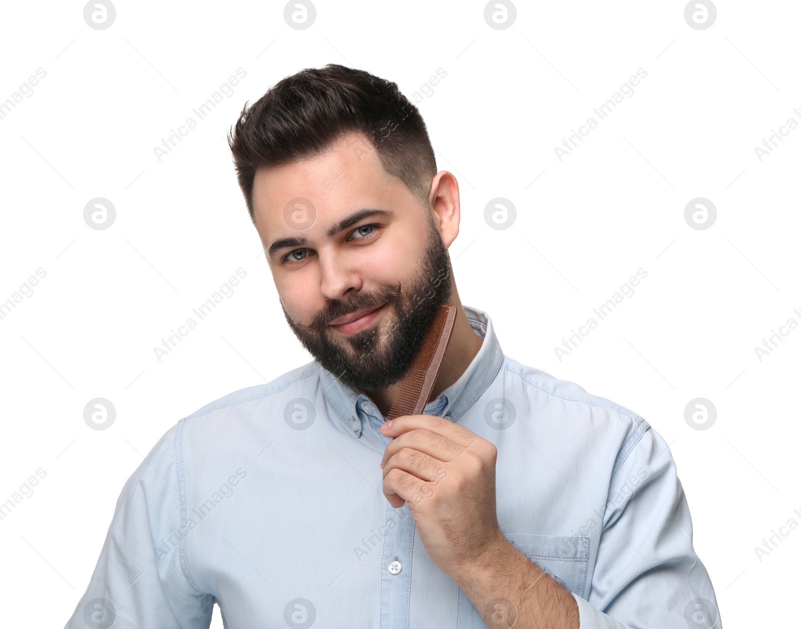 Photo of Handsome young man combing beard on white background