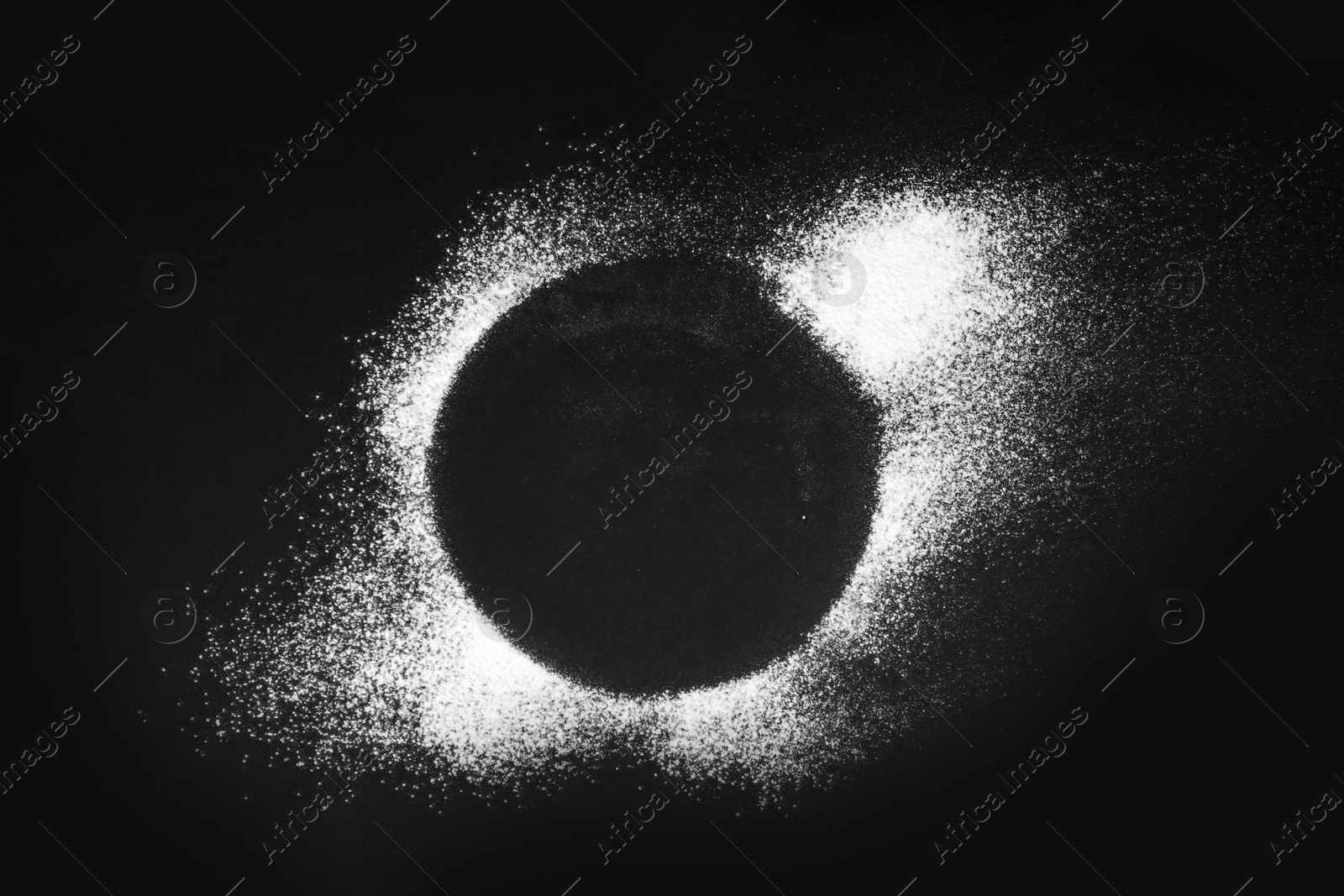 Photo of Round frame made of flour on black table, top view. Space for text