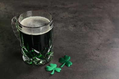 Photo of St. Patrick's day celebration. Green beer with decorative clover leaves on grey table. Space for text